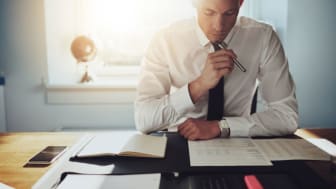 picture of well-dressed man at desk studying financial reports