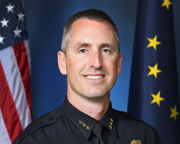 Cropped portrait of a man with short grayish hair in a police uniform looking directly into the camera.