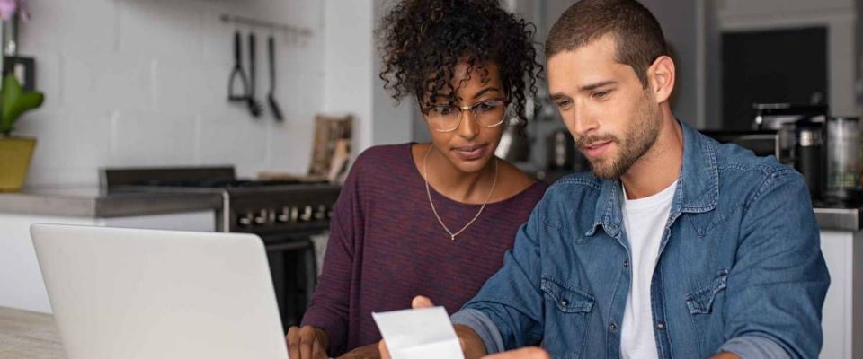 Young couple sitting at table looking at bills