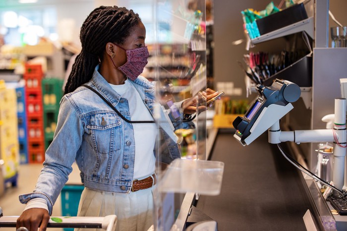 A woman paying at a kiosk with a mobile wallet.