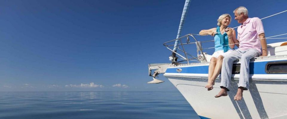 A happy senior couple sitting on the front of a sail boat on a calm blue sea