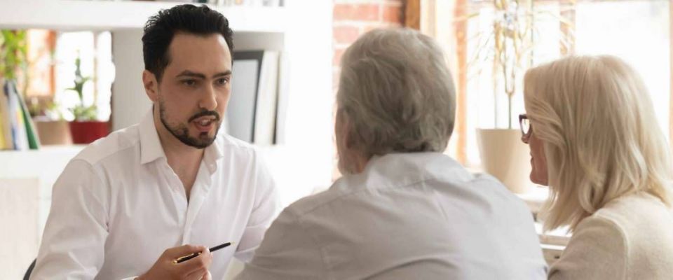 Young man faces older couple, sitting in office, discussing business