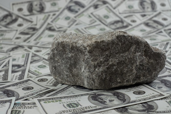 A rock sitting on piles of money.