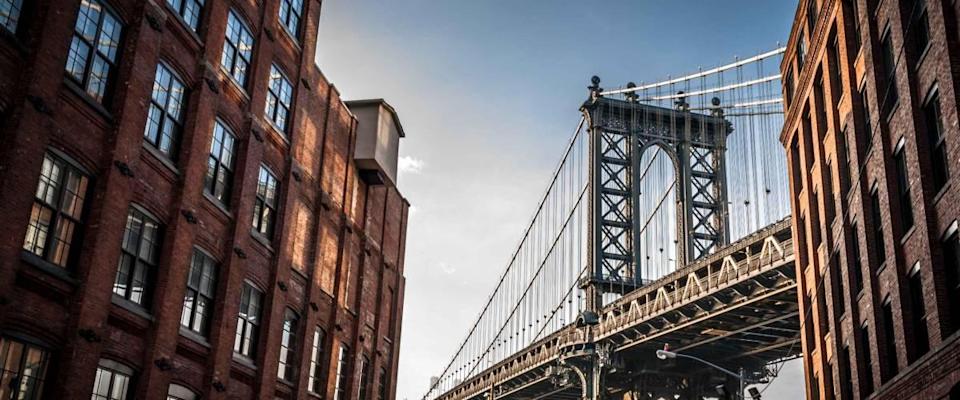 Manhattan bridge seen from a narrow alley enclosed by two brick buildings on a sunny day in summer