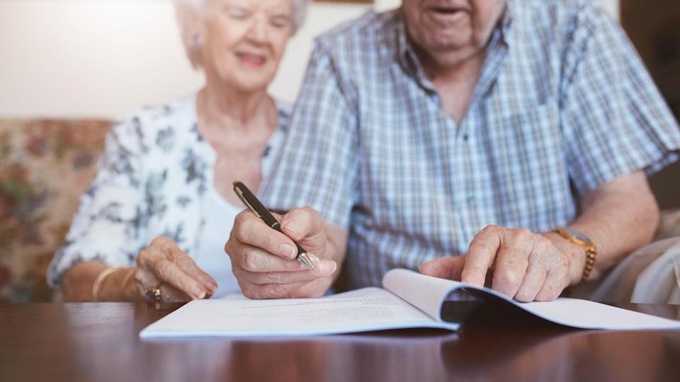 older senior couple signing a packet of documents