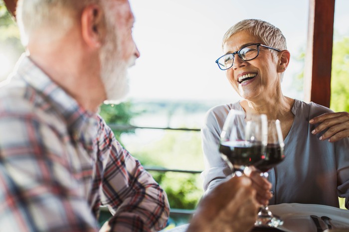 Smiling older man and woman clinking wine glasses