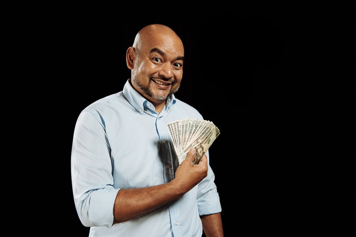 A man is holding cash fanned out and looking pleased.