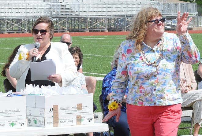 Dee Schoof, right, waves to the crowd sitting in the Salina Stadium bleachers as Superintendent for USD 305 Salina Public Schools Linn Exline announces that Schoof is retiring after this school year after completing 31 years of service to the Salina Public Schools during the retirement recognition ceremony on Sunday afternoon.