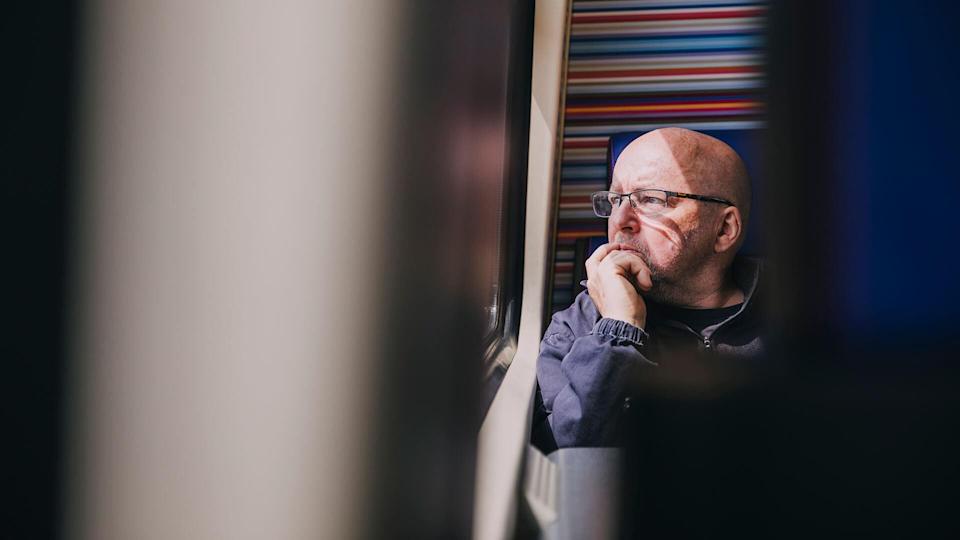 An older man sitting alone on a train in Amsterdam.