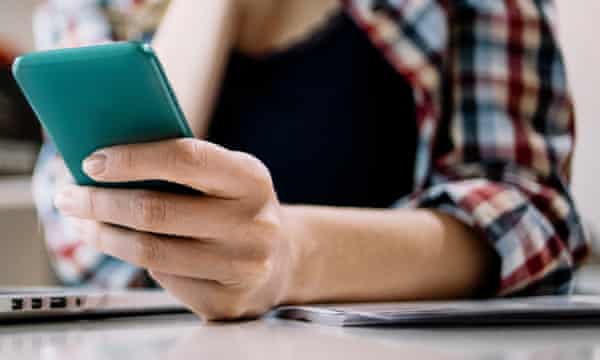 Woman looking at phone at her office desk