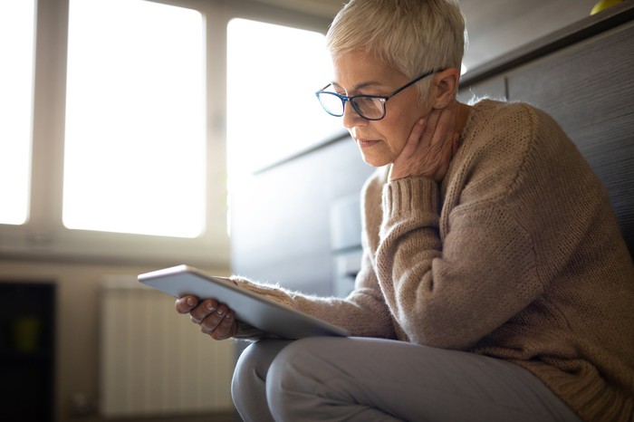 Mature woman staring at a tablet with a worried look on her face.