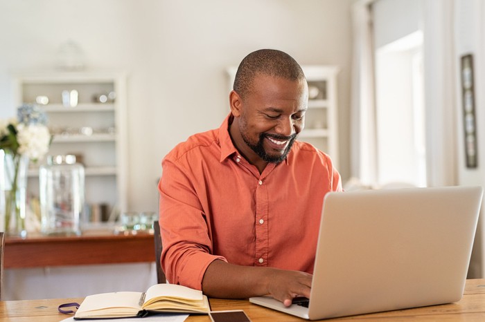 Smiling man typing on laptop