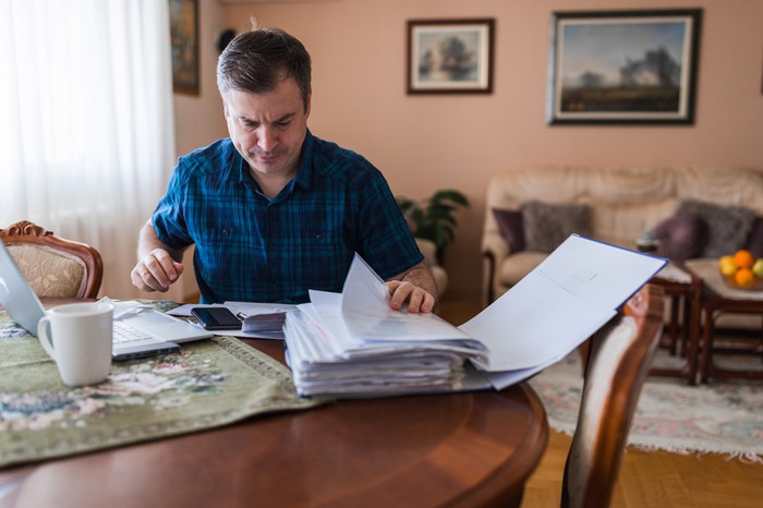 Person at table flipping through big pile of papers.