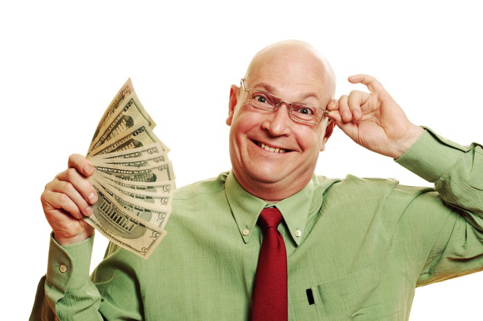 A happy bespectacled person is holding a wad of cash.