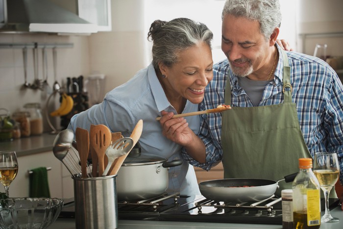 Two people cooking at stove.